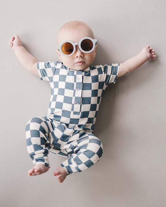 Baby laying down wearing blue and white checkered short sleeve bamboo jumsuit from Lucky Panda Kids. Sold by MilkbabyCo