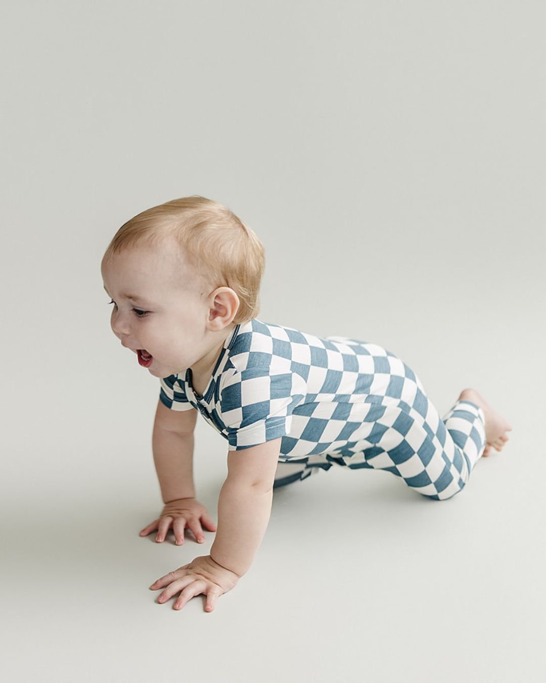 Baby crawling and wearing blue and white checkered short sleeve bamboo jumsuit from Lucky Panda Kids. Sold by MilkbabyCo