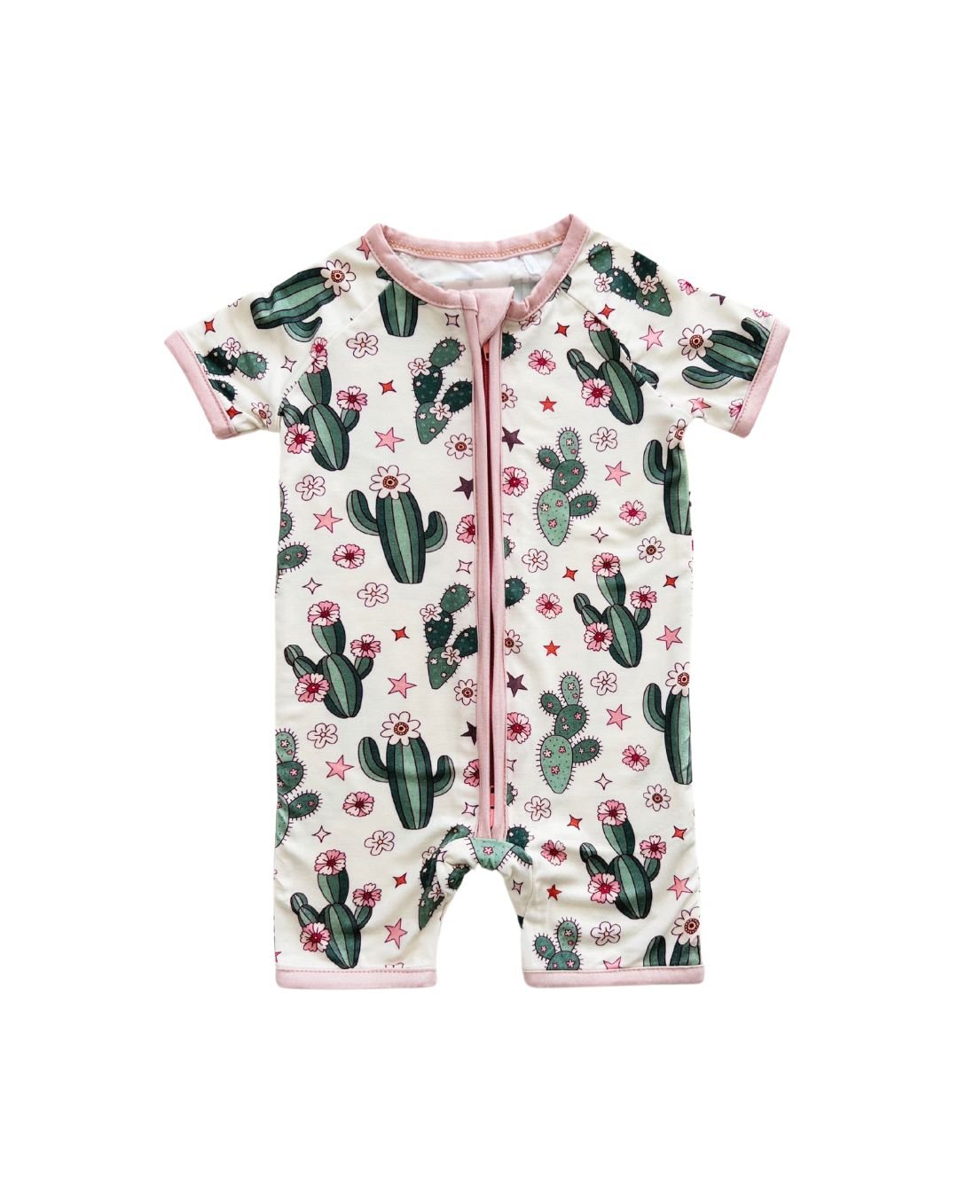 A Lucky Panda Kids cream colored short sleeve shortie romper with green cactus designs, pink trim and pink flowers and stars laid out on a white background. 