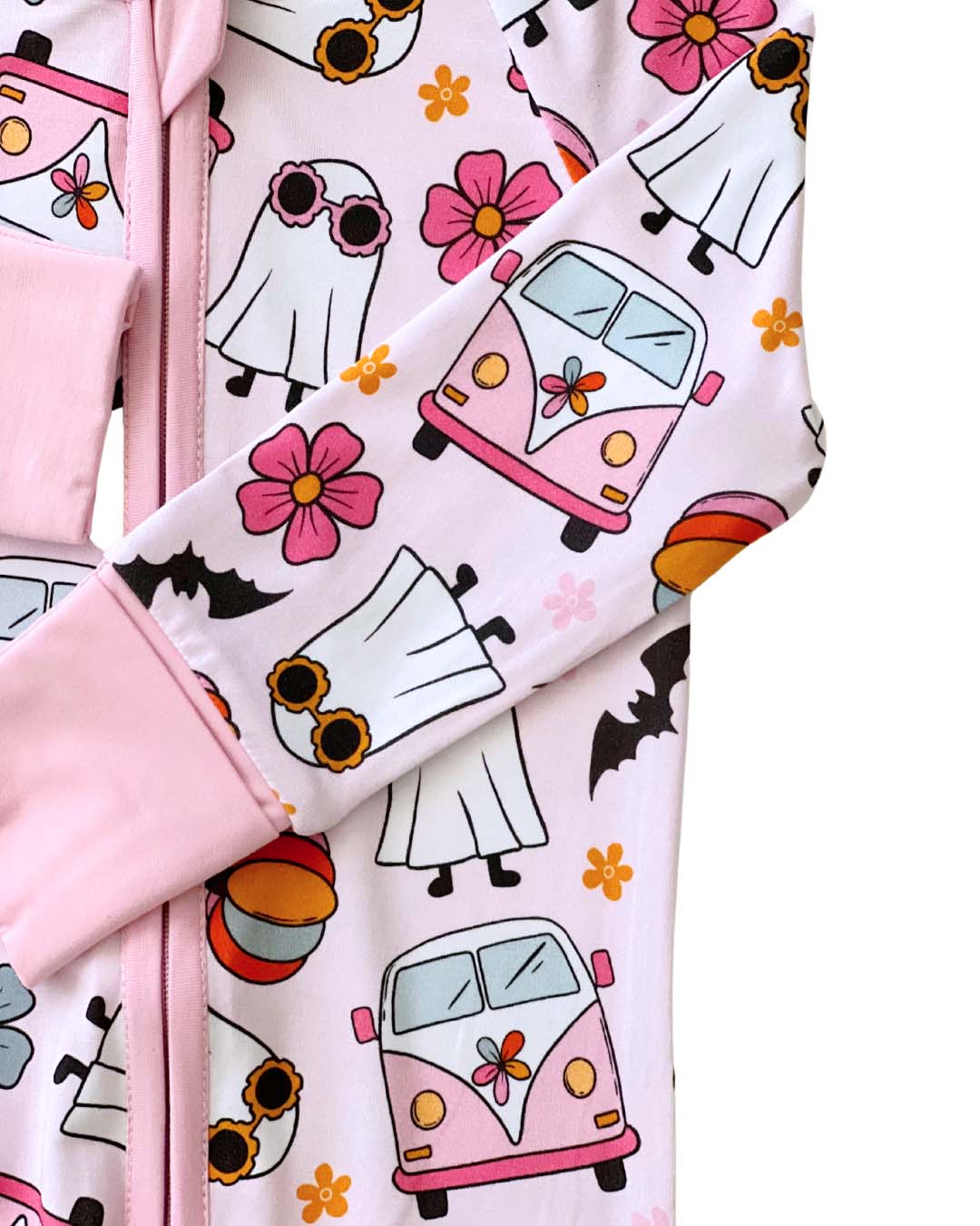 Close up detail shot of a light pink Lucky Panda Kids zip up pajama in the style of halloween. It has white ghosts, pink hippie vans, multicolored orange pumpkins, blue and pink flowers, and black bats printed on it.