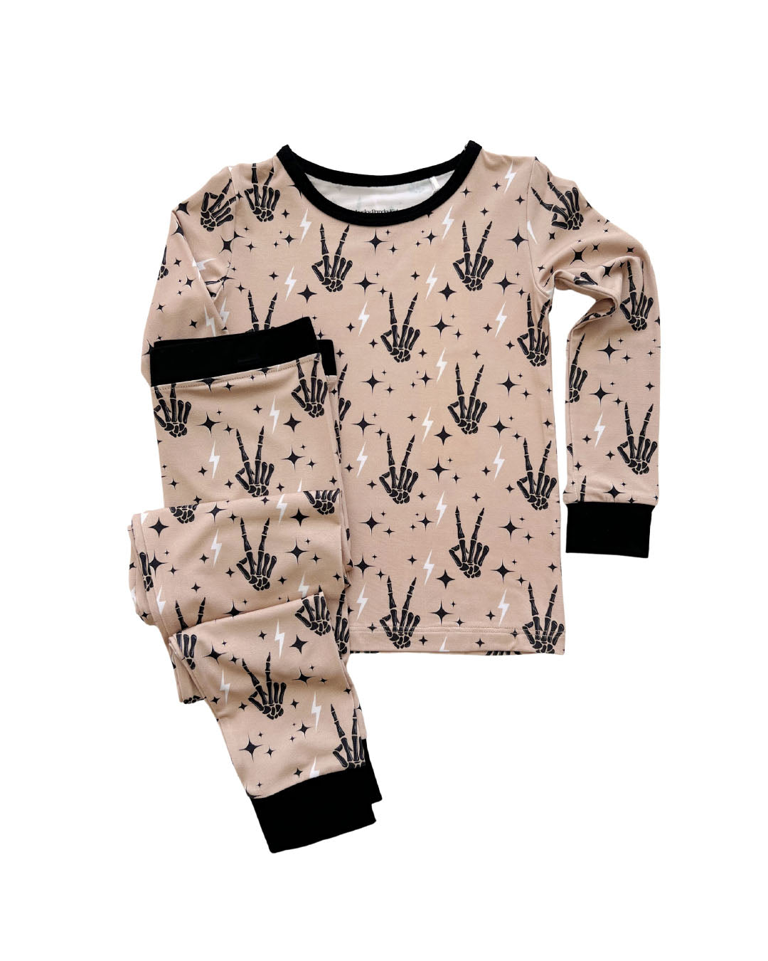 Lucky Panda Kids viscose bamboo two-piece pajama set in tan designed with black skeleton peace sign hands, white lightning bolts, and black stars laid out on a white background.